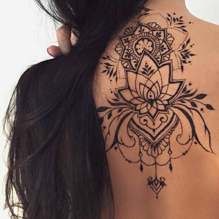 Жена с дълга тъмна коса с черна гръбна татуировка под шията, лотосово цвете от къна