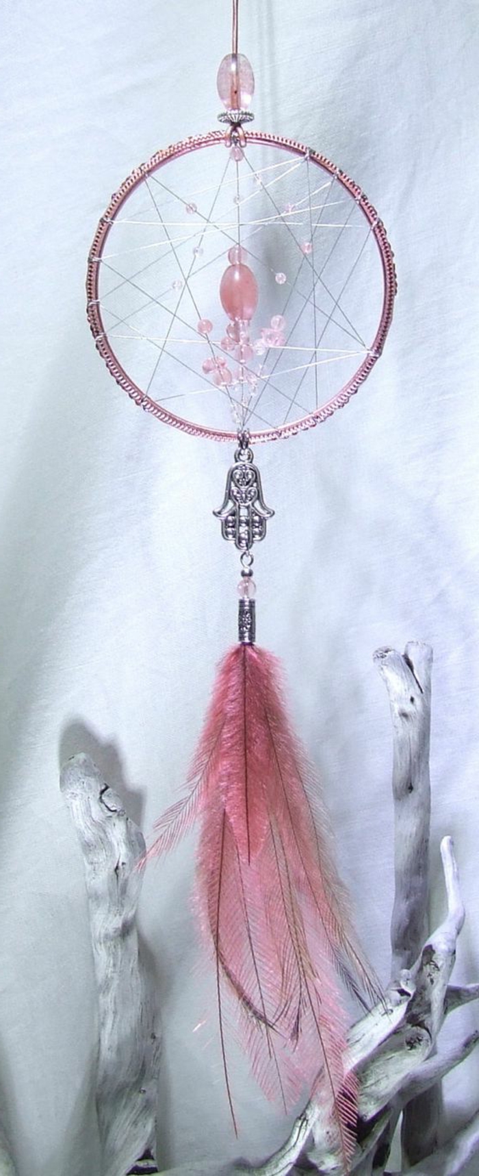 Atrapasueños con plumas de color rosa claro y cuentas de vidrio y una joyería de plata