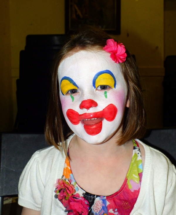 visage de clown - une fille a l'air drôle - avec une fleur dans les cheveux