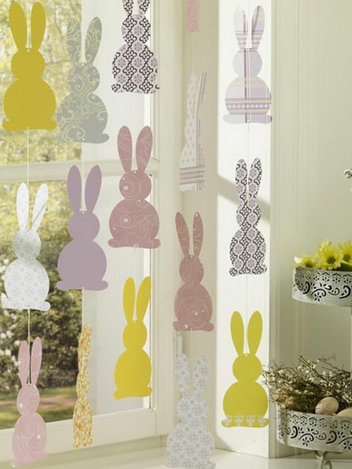 Направете великденски зайци от цветен картон, висящ на прозореца