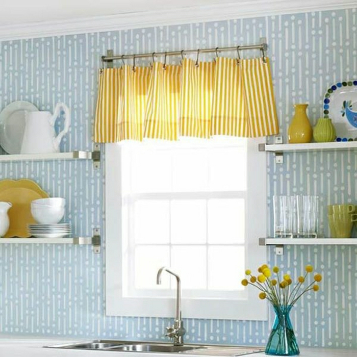 Kuhinja-plavi zidovi police posuđa od porculana plava vaza Žuti cvijet žute zavjese sudoper mali prozor