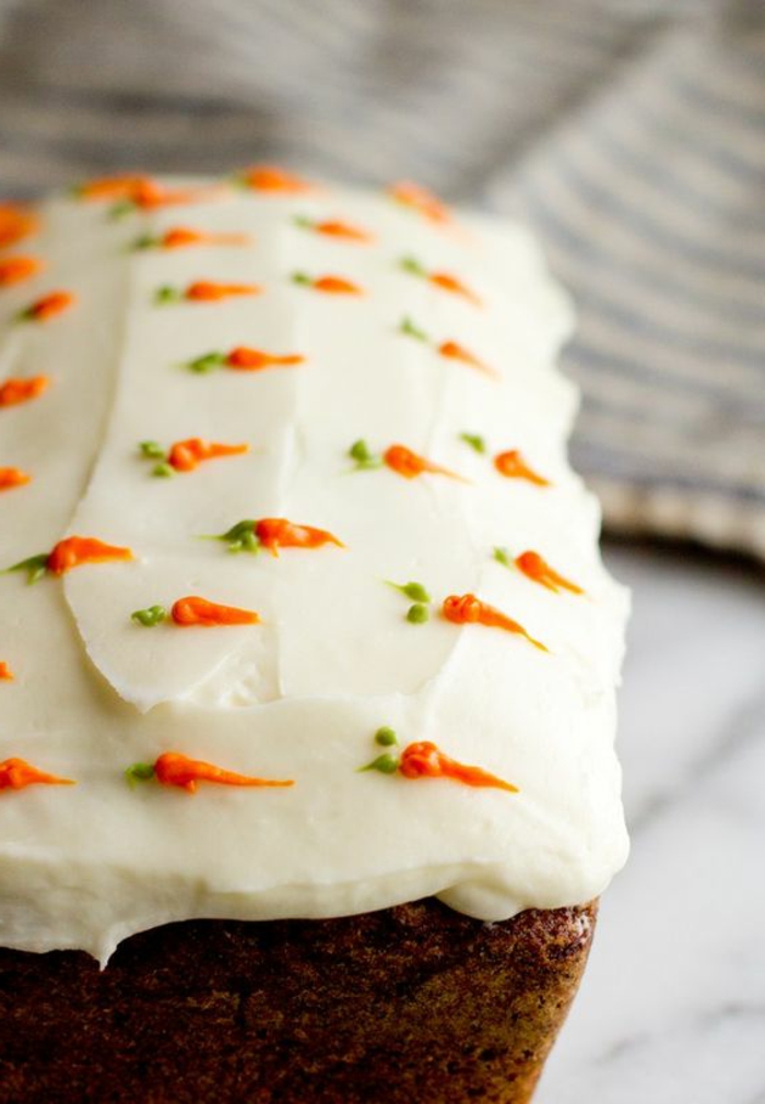 A sárgarépával díszített süteményt fehér krém díszíti
