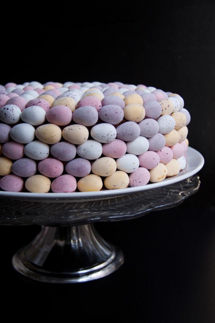 Húsvéti sütemény színes tojásokból készült, pasztell színekben egy üveg torta állványon