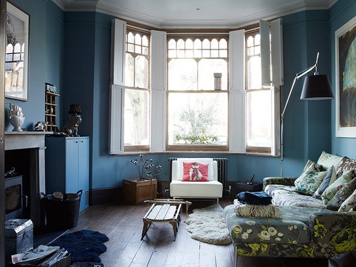غرفة المعيشة الزرقاء مع الموقد والأرضيات الخشبية ونافذة كبيرة