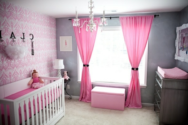 cortinas rosadas y lámparas de cristal en la habitación del bebé
