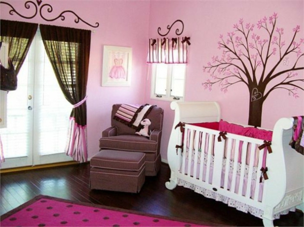 Peinture d'arbre sur le mur dans la chambre de bébé rose