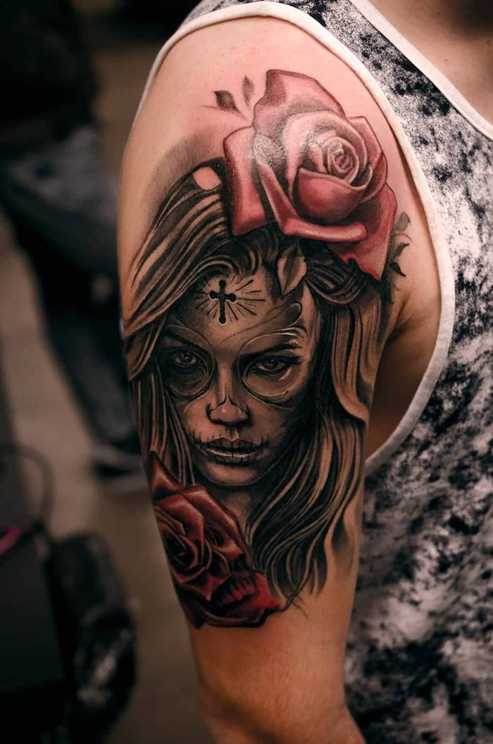 la catrina merkitys - tatuointi mies, jossa on kaksi isoa punaista ruusua ja nuori nainen ja pieni musta risti