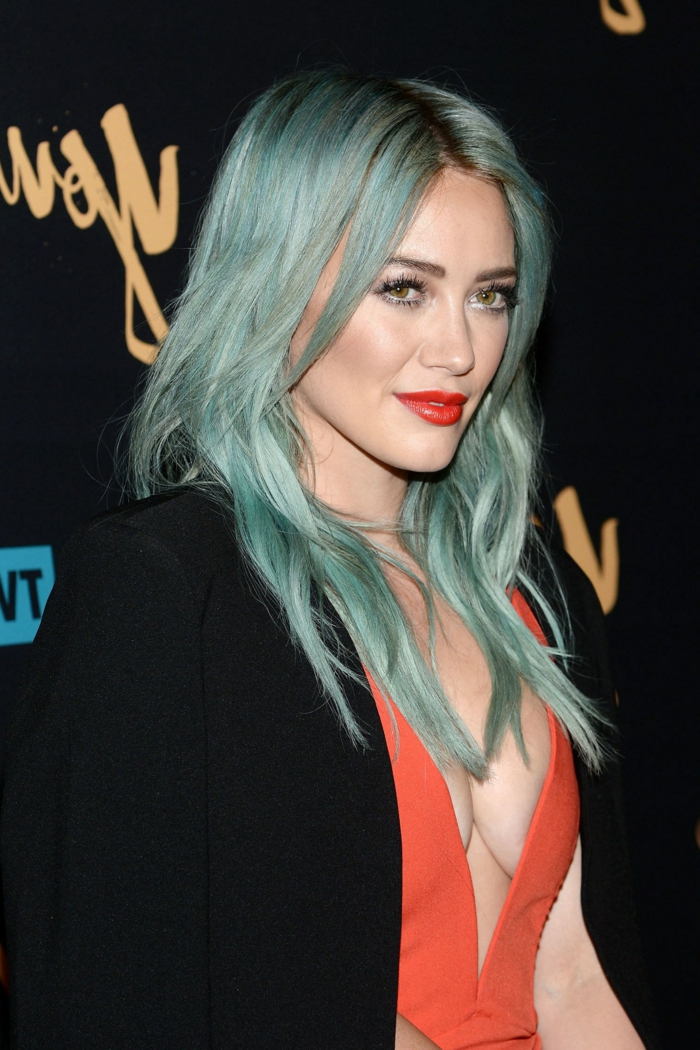 Kék haja, Hilary Duff extravagáns megjelenéssel, élénk piros ajkakkal, korall esti ruhában, fekete blézerben