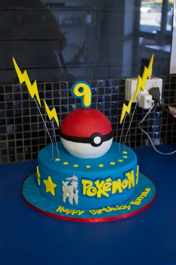 un gran pastel de pokemon azul con pokebolas rojas y dos flashes amarillos y estrellas amarillas y un encabezado amarillo