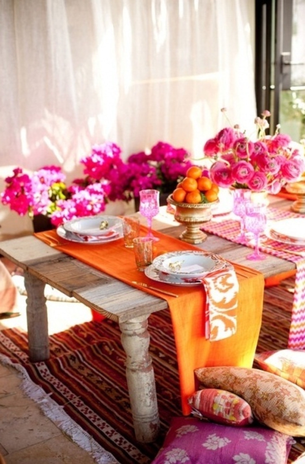 Monet modernit kukat kirkkailla väreillä ja oransseilla mandariinilla muodostavat pöydän