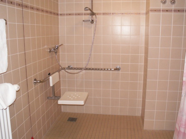 douche de plain-pied dans la petite salle de bain avec des carreaux de couleur pêche