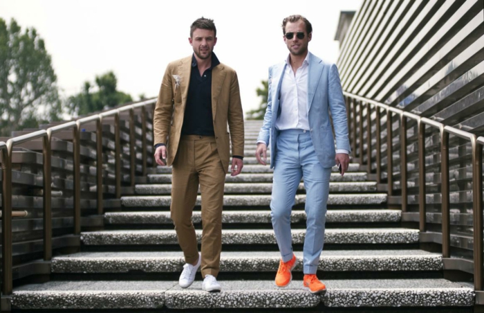 Kolege dvoje muških poslovnih partnera spuštaju se po stubama u nosi tenisice i odijelo
