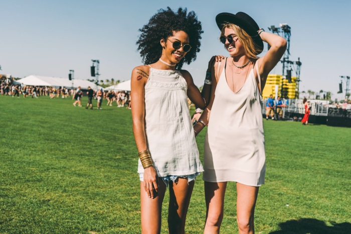hippie фестивални облекла Две красиви жени се забавляват на зеленото поле слушайки музика и се наслаждават
