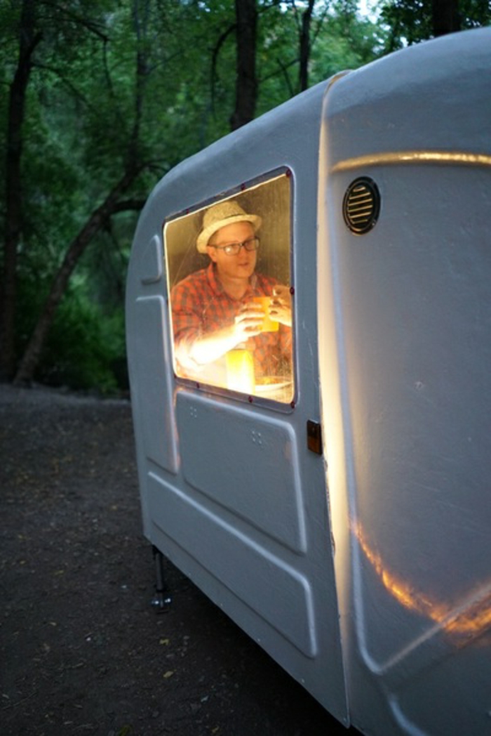Evo muškarca s šeširom s naočalama u bijelom udobnom karavanu za bicikle u šumi