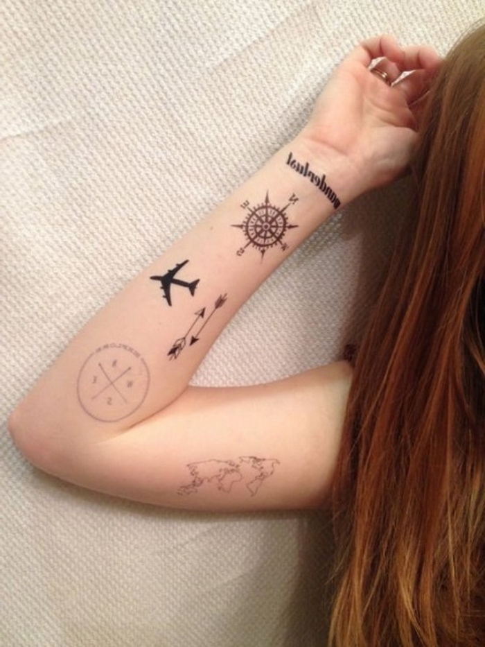 Ето една млада жена с ръка с малки черни татуировки - картата на света, летяща войска и два малки черни компаса