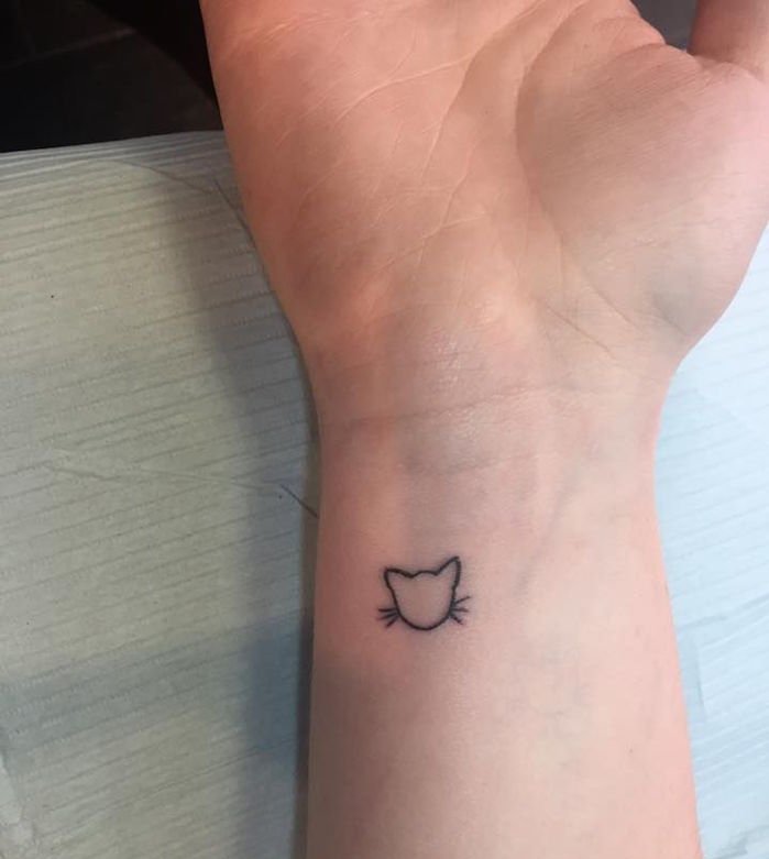itt van egy kis macska tetoválás a csuklón - egy macska hosszú fekete farkán