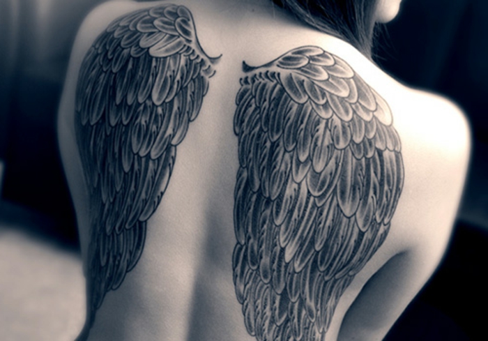 Εδώ είναι μια γυναίκα με ένα μεγάλο τατουάζ αγγέλου με μακριά μαύρα φτερά αγγέλου