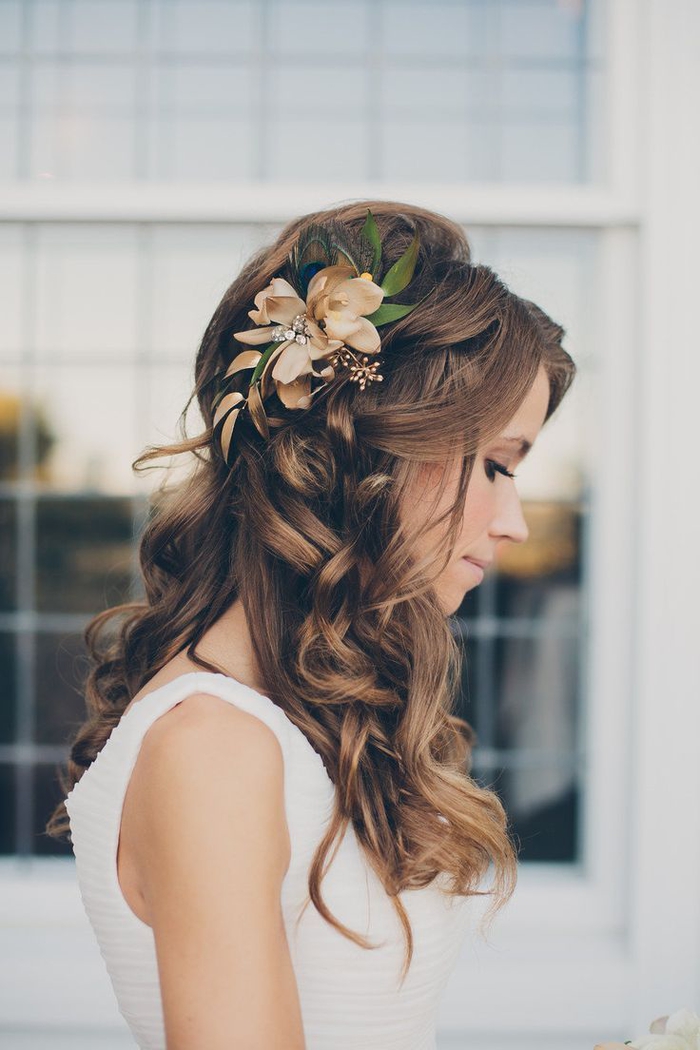 cheveux bouclés, une fleur dans les cheveux avec des feuilles vertes regard innocent coiffures de mariage