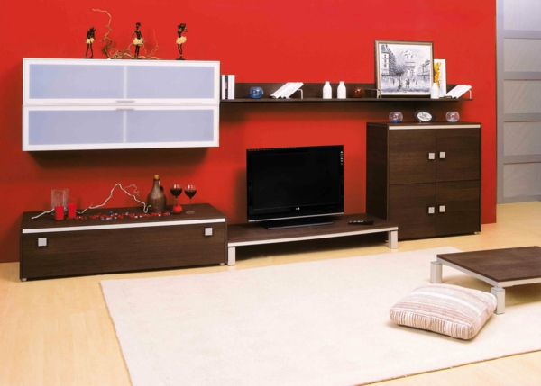 Exclusivo mobiliario de tv-una-pared-roja-detrás-y una almohada en el piso