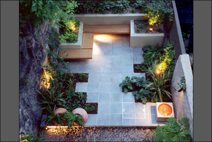 минималистична градина с множество цветни лехи с лесна грижа, кът за сядане