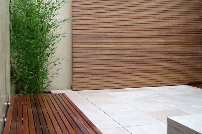 дървен екран, пейка и зелено растение, подови плочки - минималистична градина