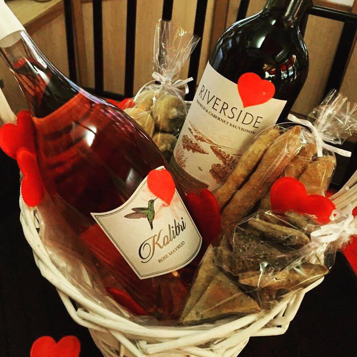 подаръчна кошница с две винени бутилки, червено вино и роза, сладкиши