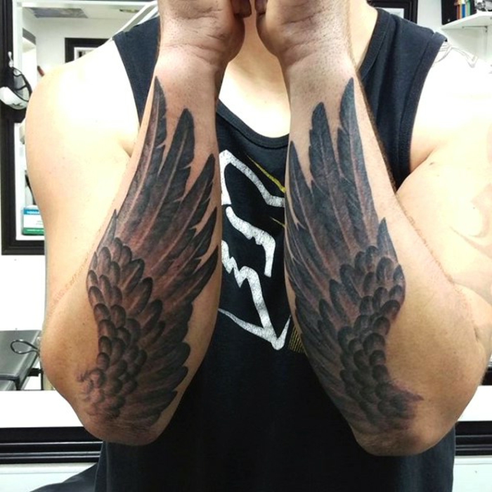 hieno käsitys tatuoiduista käsistä - tässä on kaksi kättä ja kaksi mustat enkelin siivet, joissa on pitkät höyhenet