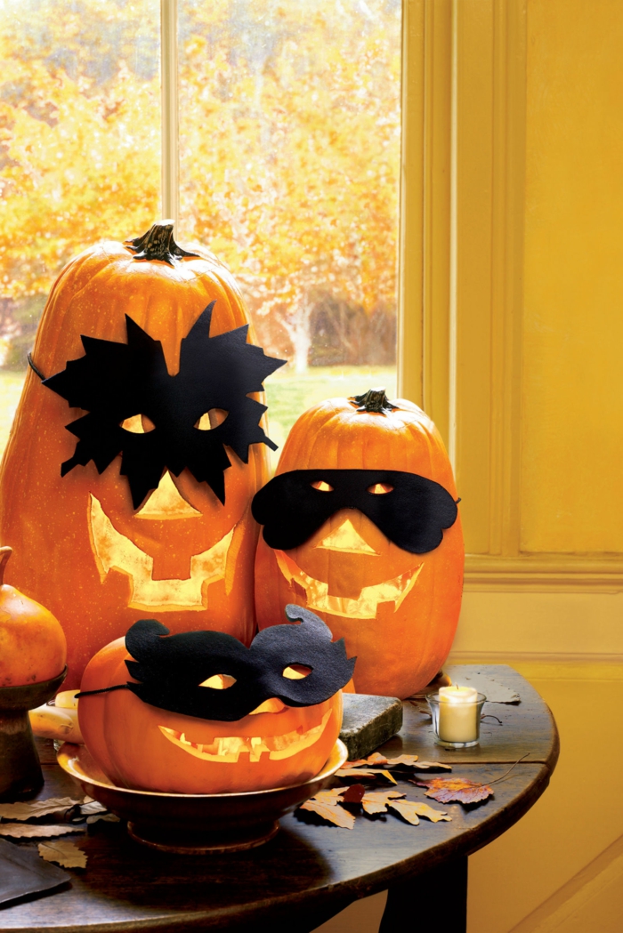 Sütőtök sütése, félelmetes sütőtök arcok maszkkal, Halloween asztali dekorációk, őszi levelek és illatos gyertyák