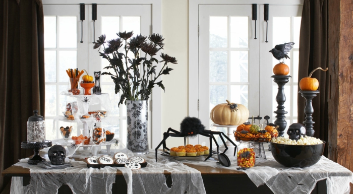 Halloween asztali dekoráció, fekete virágok, holló és koponya, party-étel kekszek és pattogatott kukorica