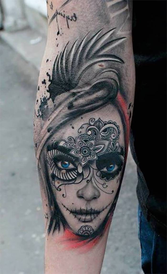 Mano con un tatuaje de una mujer joven con ojos azules y con flores blancas y labios negros - La Catrina tattoo