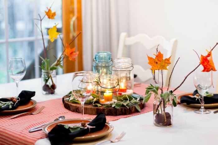 arreglando la mesa de manera otoñal, hojas de otoño y castañas en frascos de conservación, linternas pequeñas
