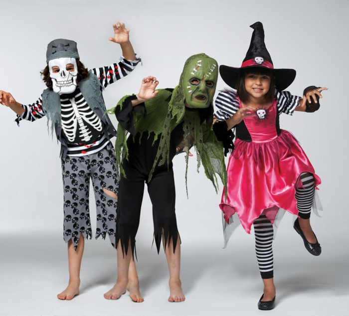 hyvät Halloween-puvut, lapset pukeutuneina luuranko, zombie ja noita, temppu tai hoito