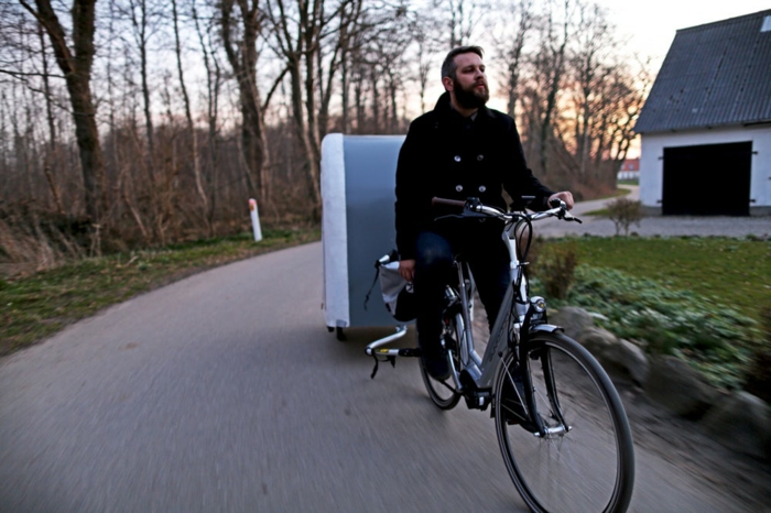 biciklist s crnim kaputom i bicikl s karavanom za bicikle