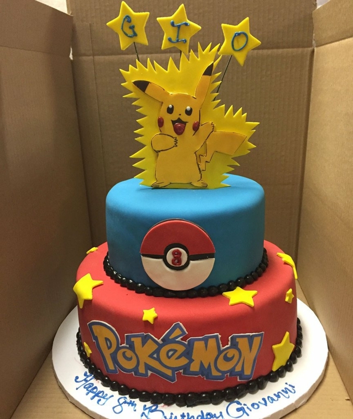 Hermosa tarta de pokemon de dos pisos con estrellas amarillas y titulares y una pequeña esencia pokemon pikachu