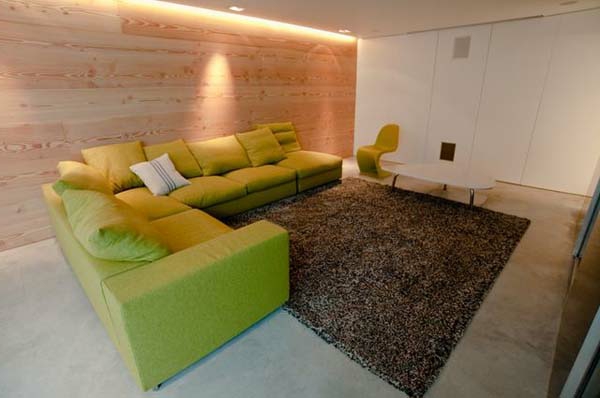 μικρό σαλόνι με ξύλινο τοίχο και πράσινο καναπέ