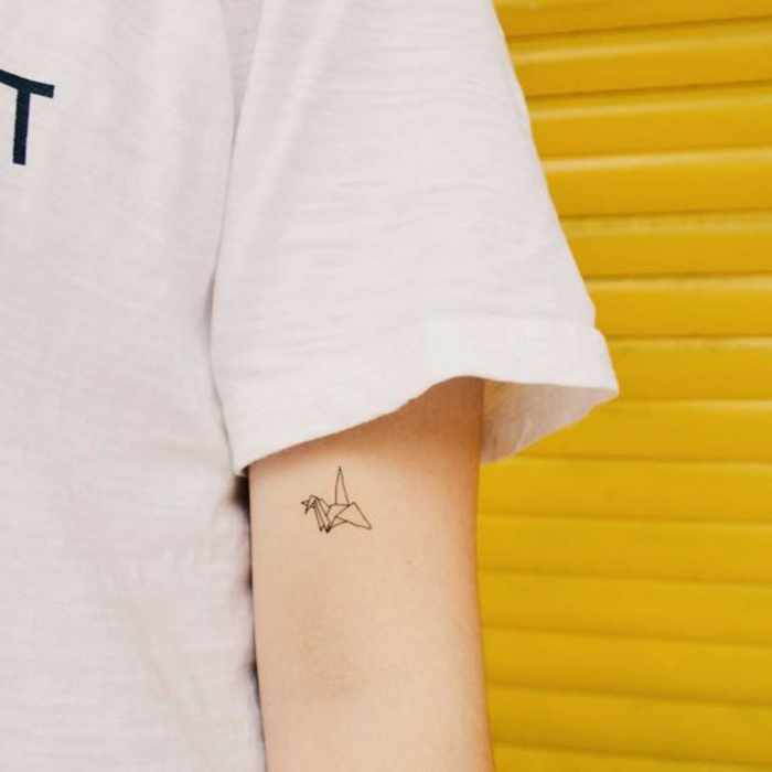 t-paita ja pieni kaunis origami tatuointi - idea tatuoinnille pieni lentävä lintu origami-motiiveilla
