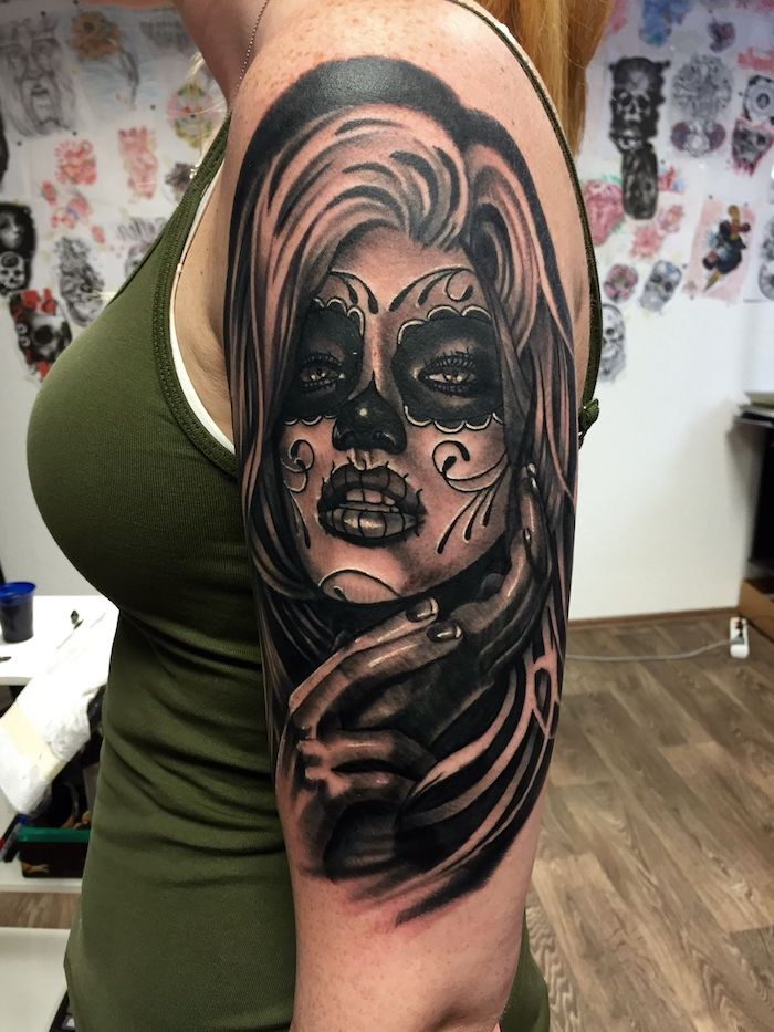 mujer joven con un gran tatuaje negro con una catrina con labios negros, ojos negros y una nariz negra