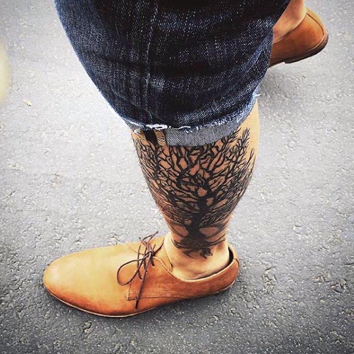 tetovaža na nozi poput stabla života čovjek s trapericama i narančastim cipelama