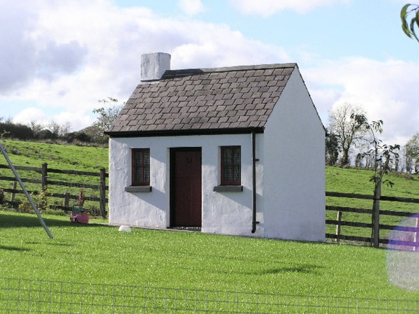 Μικρό σπίτι-οικοδόμηση-γκρι-χρώμα - που περιβάλλεται από πράσινο γρασίδι