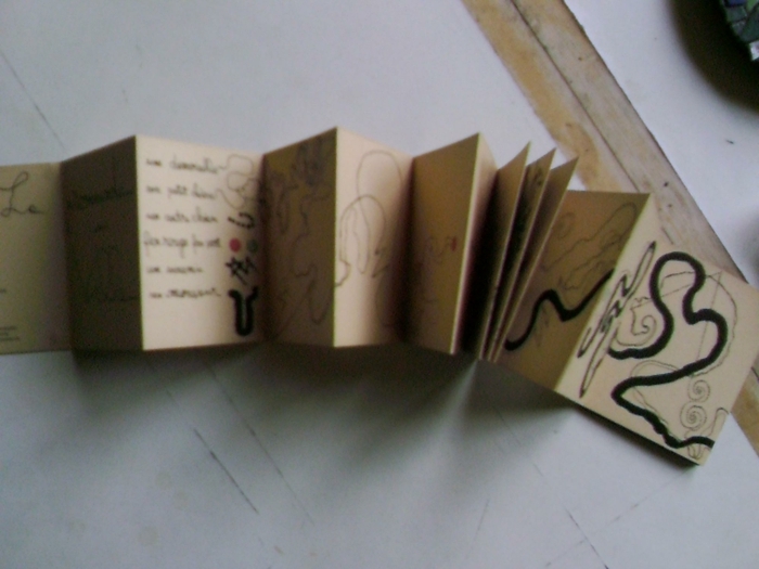 Leporello hace de cartón con inscripciones y pequeñas imágenes en color marrón