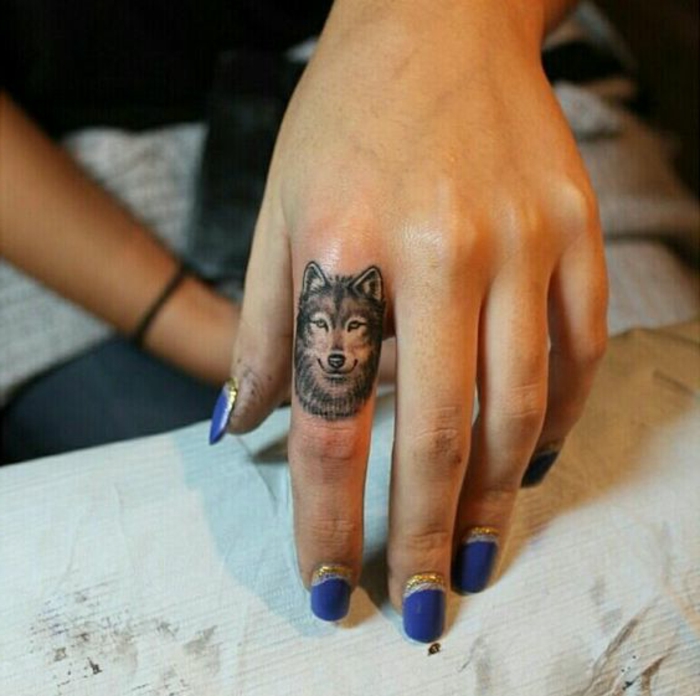една от любимите ни идеи за татуировка вълк татуировка - вълк върху пръста и лилав лак за нокти