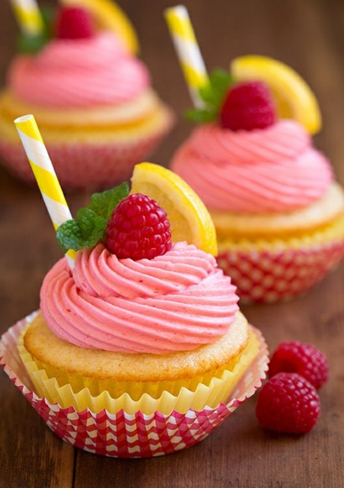 kis muffinok rózsaszín krémmel, málnával, borsmental és citrommal díszítve