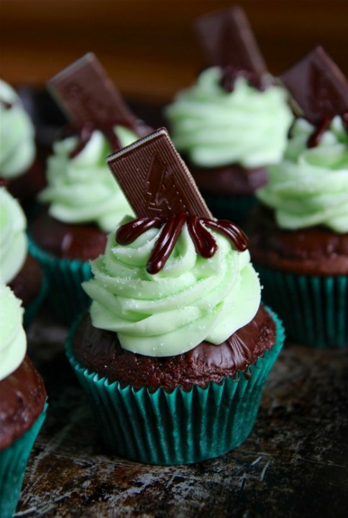 cupcake de chocolate decorado con crema verde y un trozo de chocolate