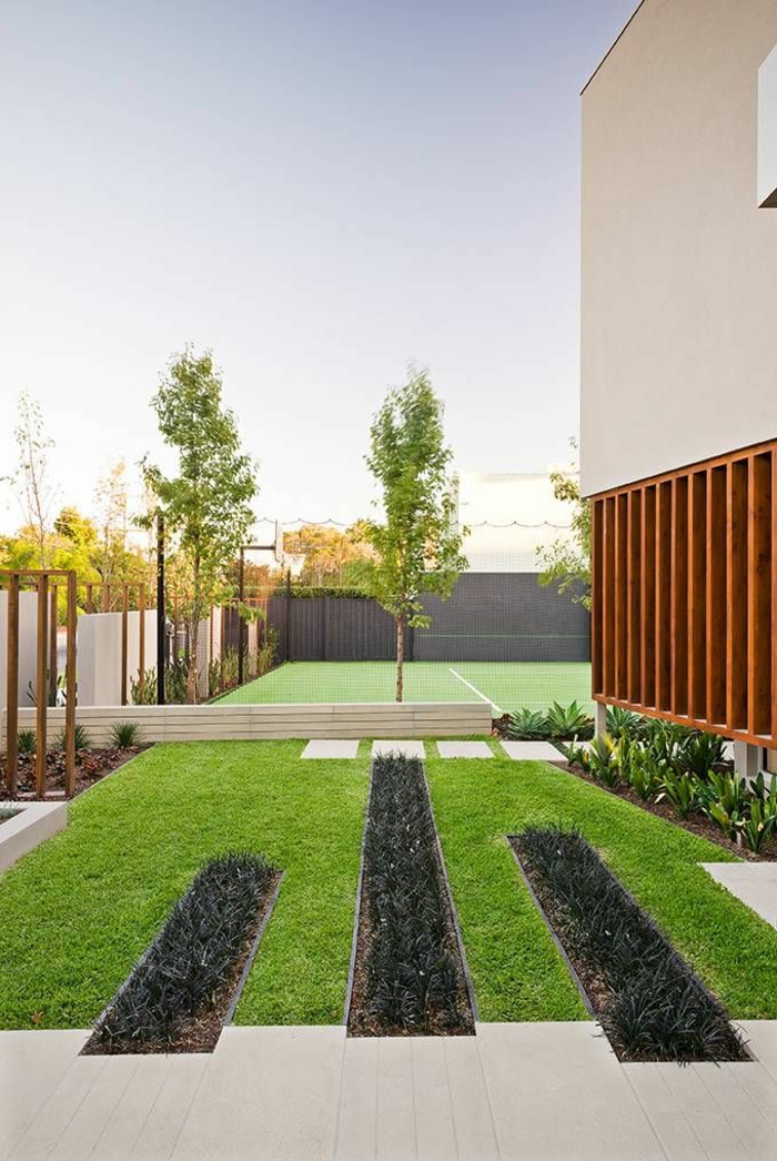 модерен предстен двор с подредени тревни площи и някои дървета, така геометрични