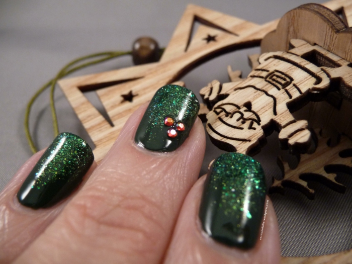 La conception de l'ongle de la Saint-Sylvestre en vert foncé, vernis à ongles paillettes, trois petits cristaux collés, forme de clou angulaire