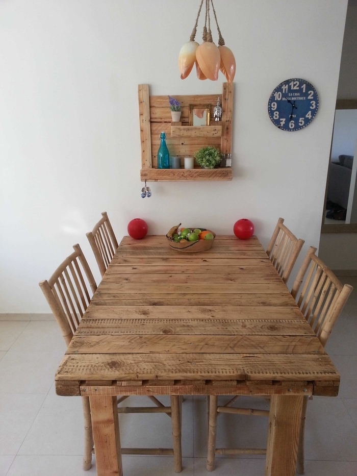 mesa de madera, sillas de madera y un estante hecho a sí mismo de paletas y madera con flores, una imagen y una botella azul