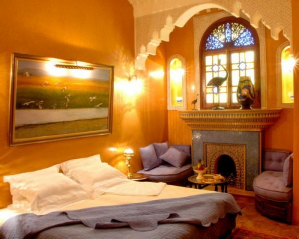 πολυτελές τζάκι και σχέδια πορτοκαλί χρώματος στο κομψό ανατολίτικο υπνοδωμάτιο