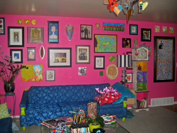 ružičasta zidna boja i mnogobrojne slike na zidu - kauč u plavoj boji