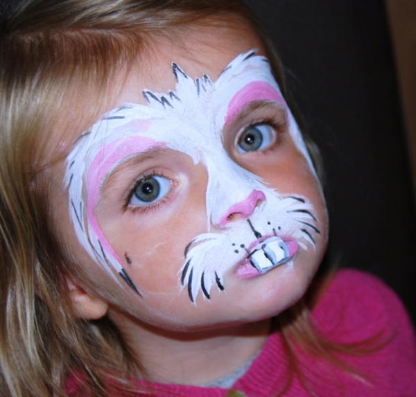 peindre le visage de lapin - une petite fille avec des yeux brillants
