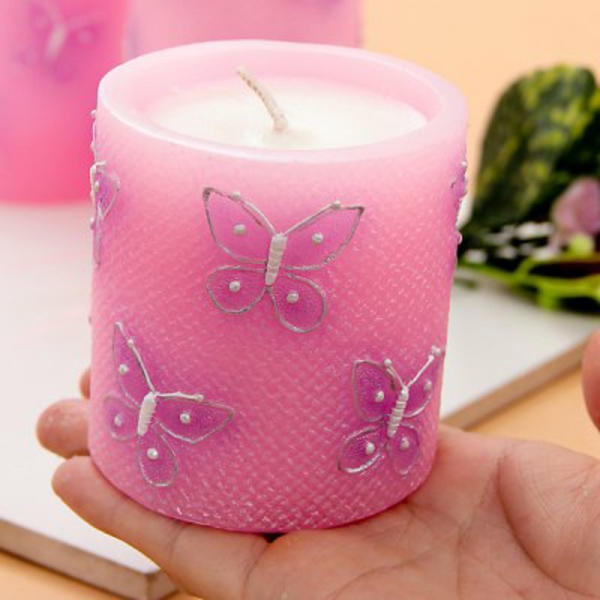 Figuras de mariposas como decoración de una vela rosada